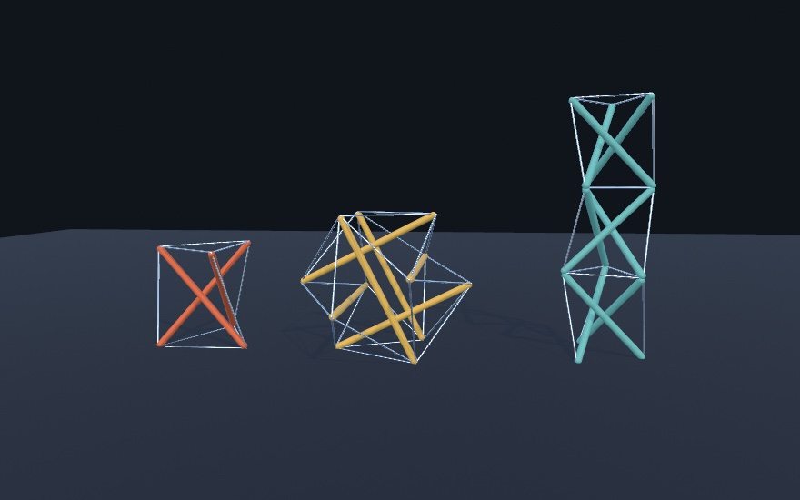 Three tensegrities standing on a dark floor, each built from colored struts and thin pale cables: an orange three-strut prism on the left, a yellow six-strut ball in the middle, and a tall teal mast of three stacked prisms on the right. No strut touches another in the first two.