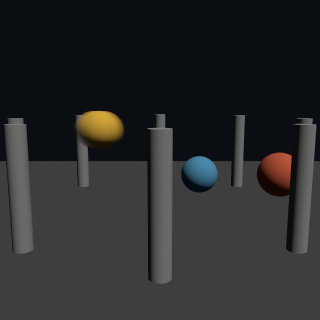 Three colored spheres orbiting among a ring of gray columns. The fast yellow sphere is smeared into a soft oval along its path, the red one is only slightly soft, the slow blue one is crisp, and the columns stay sharp